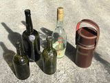 several empty wine bottles and a leather case sitting on a concrete surface