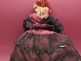 an old fashioned doll sitting on a pink surface