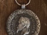 une vieille médaille en argent posée sur une table en bois, accompagnée d'un porte-clés