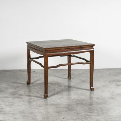 une petite table en bois avec un plateau en marbre posée sur un sol en béton