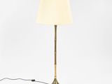 a gold floor lamp with a white shade on a white background