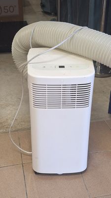 un climatiseur blanc posé par terre près d'une fenêtre