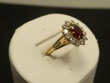 une image représentant une bague en or sertie d'une pierre rouge entourée de diamants blancs