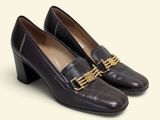 the woman ' s shoes are made of leather and have a gold chain