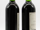 two bottles of red wine sitting next to each other on a white surface