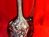 un vase en verre rouge et blanc posé sur un tissu rouge