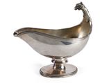 une saucière ancienne en métal argenté, posée sur un socle et surmontée d'un oiseau