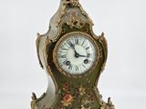 a green and gold clock sitting on a white surface