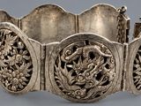 a silver bracelet with a bird and flowers design on it
