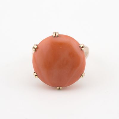 une image représentant une bague de couleur corail posée sur une surface blanche