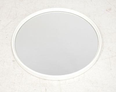 un miroir rond accroché au mur de la salle de bains