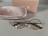une paire de lunettes avec son étui, posée sur la table à côté d'une boîte de lunettes