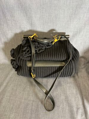 un sac à main en tricot gris auquel est attaché un téléphone portable