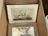 plusieurs tableaux, encadrés ou non, rangés dans une boîte posée sur une table