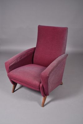 an image of a pink chair with wooden legs on a grey background