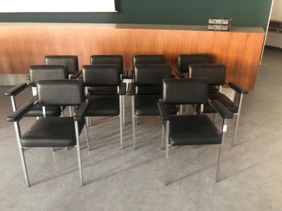 de nombreuses chaises noires dans une pièce aux murs verts