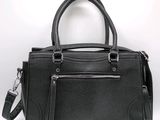 the black leather handbag is sitting on a white surface