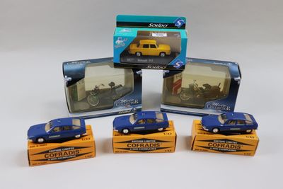 Quatre petites voitures sont posées dans une boîte sur une surface blanche.