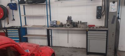 une voiture rouge garée dans un garage, à côté d'un établi