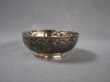 an antique silver bowl on a table with a gray background