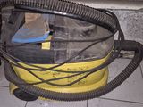 un aspirateur jaune et noir posé sur un sol carrelé