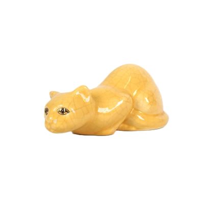 une figurine de chat jaune posée sur une surface blanche