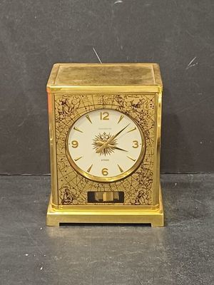 a gold clock sitting on a table with a black background