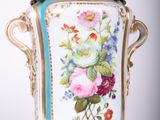 a vase with flowers painted on it sitting on a stand
