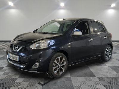 the black nissan mico is parked in a room with a checkered floor