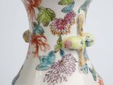 a white vase with colorful flowers on it on a table