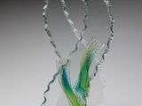 une photo d'une sculpture en verre représentant un oiseau posée sur un socle