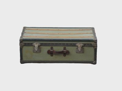 une vieille valise posée sur une surface blanche