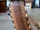 a close up of a chair with a seat made of wood and leather