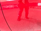 a reflection of two people standing in a red car