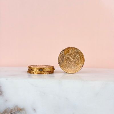 a gold coin sitting on top of a marble slab next to a pink background