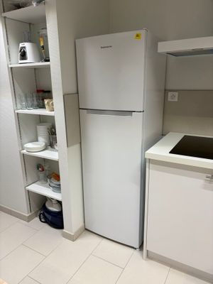 une cuisine équipée d'un réfrigérateur, d'un évier et d'étagères