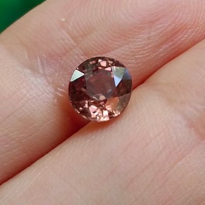 a close up of a person holding a pink diamond in their hand