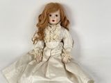 a doll that is sitting on the floor with a white dress