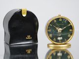 une petite horloge posée à côté d'une autre petite horloge sur une table