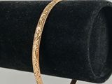 un gros plan d'un bracelet en or posé sur un présentoir à bagues noir