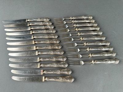 six silverplated knives and six knives on a table