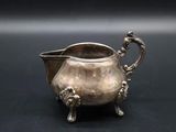 an antique silver plated creamer on a black background
