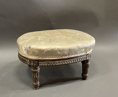 an antique foot stool with a beige upholstered seat