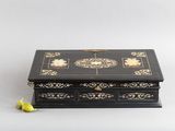 une boîte noire et dorée posée sur une table blanche