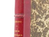 an old red book sitting on top of a table next to a white wall