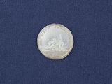 a silver coin with a picture of a man and a horse on it