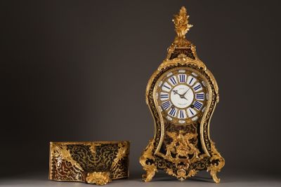 a gold clock sitting next to a box on a table