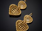 two gold heart shaped earrings with diamonds on a black surface