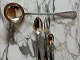 a silver spoon, spoon and spoon rest on a marble table