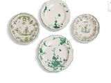 quatre assiettes recouvertes de peinture verte sont disposées sur une surface blanche